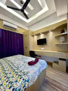 a bedroom with a bed and a desk with a television at Infinity Haven in Greater Noida