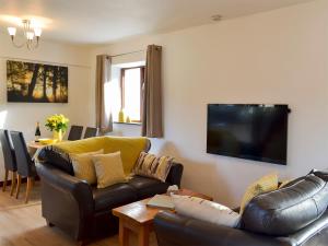 a living room with a couch and a tv on the wall at Discovery in Cheriton Bishop
