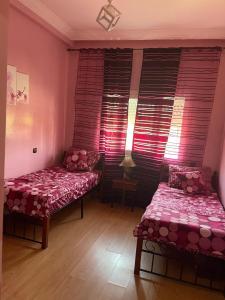 two beds in a room with pink walls and windows at Confort & Emplacement, Pieds dans l'eau in Mansouria