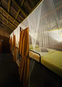 a bed in a room with a mosquito net at Pepper Hills Hostel & Cottages in Ella