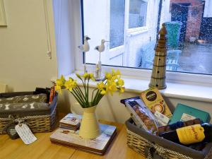 a vase with flowers on a table with a window at Billy Napp's Cottage in Filey