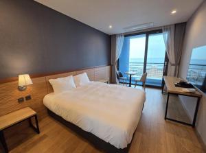 a hotel room with a bed and a desk and a window at Nova Stay Gangneung in Chumunjin