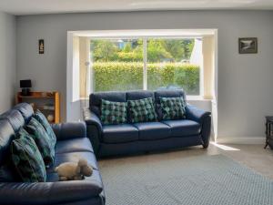 a living room with a blue couch and a window at Rotherwood in Portinscale