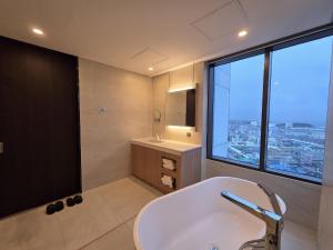 a bathroom with a tub and a sink and a window at Nova Stay Gangneung in Chumunjin +29 photos
