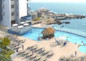 a resort with a pool and chairs and the ocean at Pingel Apartment Vista Mar in Viña del Mar