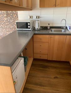 a small kitchen with a microwave and a sink at Pingel Apartment Vista Mar in Viña del Mar