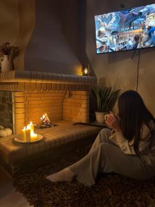 a woman sitting on the floor in front of a fireplace at Ανέμη in Panayía