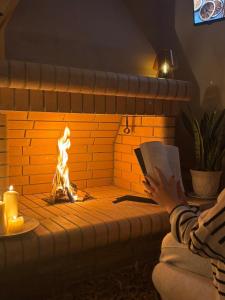 a person reading a book in front of a fireplace at Ανέμη in Panayía