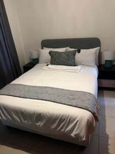 a bed with white sheets and pillows in a room at Waterfall Deluxe ll in Rustenburg +14 photos