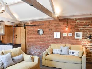 ein Wohnzimmer mit 2 Sofas und einer Ziegelwand in der Unterkunft Primrose in Scruton