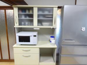 a kitchen with a microwave and a refrigerator at 豊橋南栄駅徒歩1分 最大9名一棟貸 ホタルヤ Guest House Hotaruya Toyohashi Minami Sakae in Toyohashi
