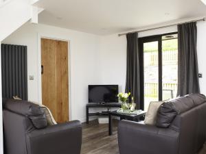 Sala de estar con 2 sofás de cuero y TV en Ash Barn - Fernhill Farm, en Ryde