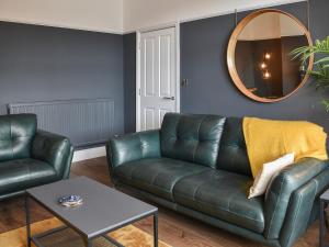 ein Wohnzimmer mit einem Ledersofa und einem Spiegel in der Unterkunft Ty Isaf in Barmouth