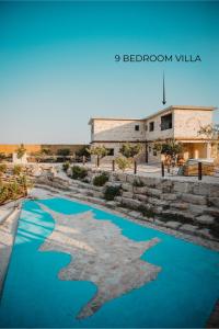 a pool of blue water in front of a building at Kleos Noble Retreat - Private Estate in Limassol