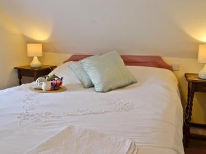 een wit bed met een dienblad met bloemen erop bij Dylasau Cottage in Capel Garmon