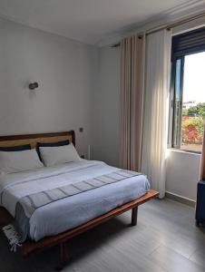 a bedroom with a large bed with a window at Hakuna Matata Apartment in Munyonyo in Kampala
