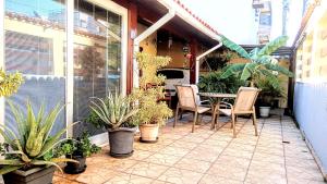 a patio with a table and chairs and plants at Pousada Colonial in Macaé