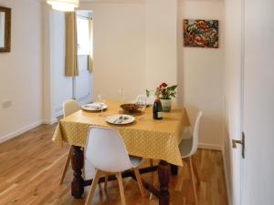 tavolo da pranzo con panno giallo e sedie bianche di Fawns Cottage a Culmstock