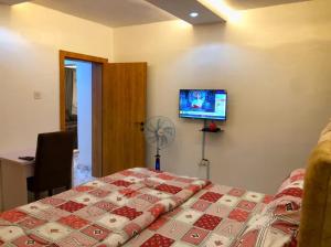 a bedroom with a bed and a tv on the wall at Debby Residence in Ijaiye
