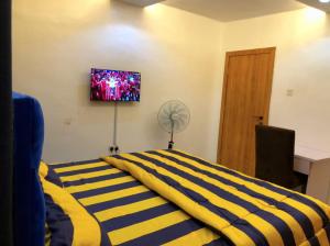 a bedroom with a bed with a yellow and blue striped blanket at Debby Residence in Ijaiye