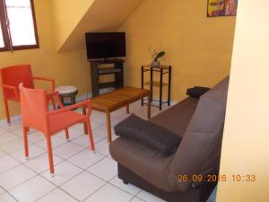 a living room with a couch and chairs and a tv at laréunion in Maison Henou