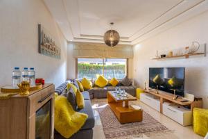 a living room with a couch and a tv at Spacious luxury apartment with pool in Bouznika