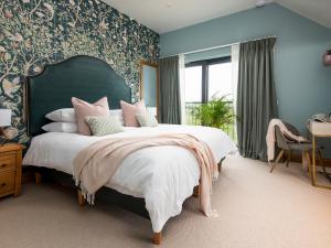 a bedroom with a large bed with a green headboard at The Cart House in Duns