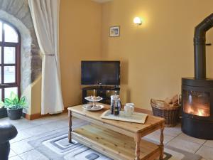 a living room with a wood stove and a coffee table at The Stables- Osb in Penbryn