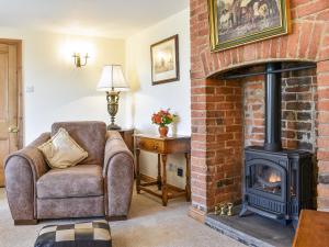 a living room with a brick fireplace and a chair at Beech Cottage in Somersal Herbert