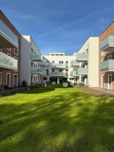 a large building with a grass yard in front of it at Ferienwohnung Sonnenufer Residenz am See in Neuruppin in Neuruppin