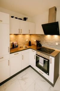 a kitchen with white cabinets and a sink at Modernes Apartment mit 180° Bergblick in Buchenberg