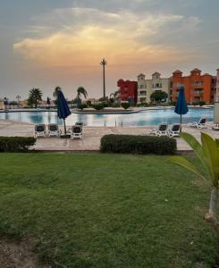 - une piscine avec des chaises et des parasols dans un complexe dans l'établissement Amer Group Villas and Chalets on the Pool, à Ain Sokhna