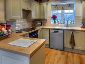 a kitchen with white cabinets and a sink and a window at Brompton Lodge in Ganton +23 photos