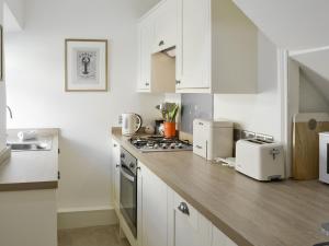 a kitchen with white cabinets and a wooden counter top at Grosvenor Cottage in Alnmouth