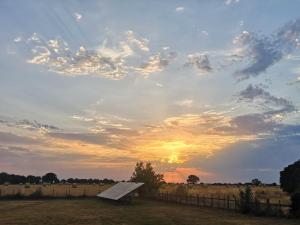 a bench in a field with a sunset in the background at Elm Barn View in Freethorpe