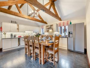 SculthorpeにあるWoodpecker Barn - Cwlのキッチン(木製のテーブル、椅子、冷蔵庫付)