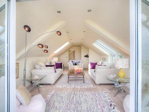 un salon avec des meubles blancs et des coussins violets dans l'établissement Ty Gan Y Mor, à Nefyn 12 autres photos