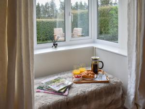 Ein Tablett mit Speisen und Getränken auf einem Tisch neben einem Fenster in der Unterkunft Manor Park Cottage in Knitsley