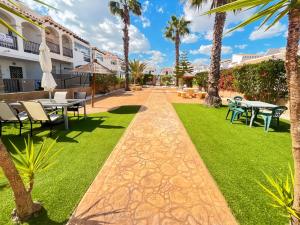 a courtyard with tables and chairs and palm trees at Modern Duplex with Solarium Community Pool in Orihuela Costa in Orihuela
