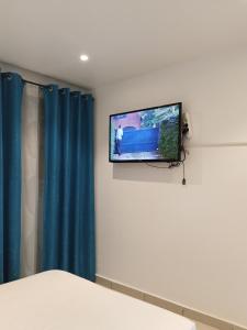 een flatscreen-tv aan een muur in een slaapkamer bij Houcine appartement in 'Aïn el Turk