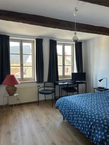 a bedroom with a bed and a table and windows at Maison de la Fontaine in Hierges