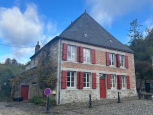 an old brick building with red shutters on it at Maison de la Fontaine in Hierges