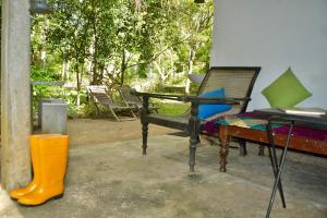 een terras met een bank, een tafel en gele laarzen bij EcoBlueprint Garden in Pannala