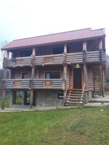 une maison en rondins avec une terrasse couverte et des escaliers à l'avant. dans l'établissement Садиба Bokoras, à Vyshka