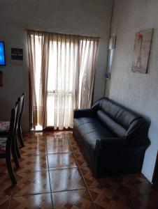 een zwarte leren bank in een woonkamer met een raam bij Casa en el Chuy in Barra del Chuy