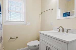 a white bathroom with a toilet and a sink at Second Row Stunning Ocean and Marsh Views in Holden Beach +24 photos