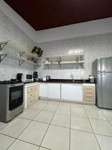 a large kitchen with white tile floors and stainless steel appliances at Voila Hostel in Florianópolis