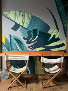 a wooden table with two chairs in front of a mural at Voila Hostel in Florianópolis