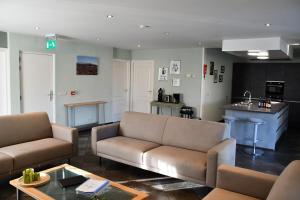 a living room with two couches and a kitchen at La Bordure de la Forêt in Sourbrodt