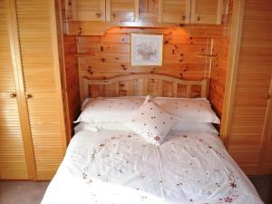 a bedroom with a white bed with wooden walls at Ashness in Keswick